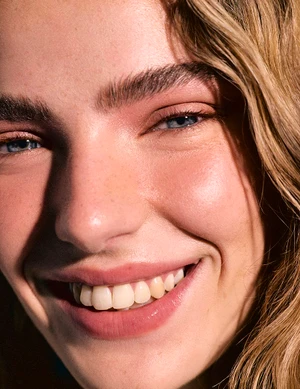 Close-up portrait of a smiling woman with blue eyes and blonde hair for Harper's Bazaar España Sunny Pills editorial.