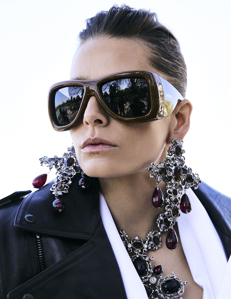 Close-up portrait of model Hana Soukupova wearing oversized brown sunglasses and elaborate crystal earrings for Harper's Bazaar España.