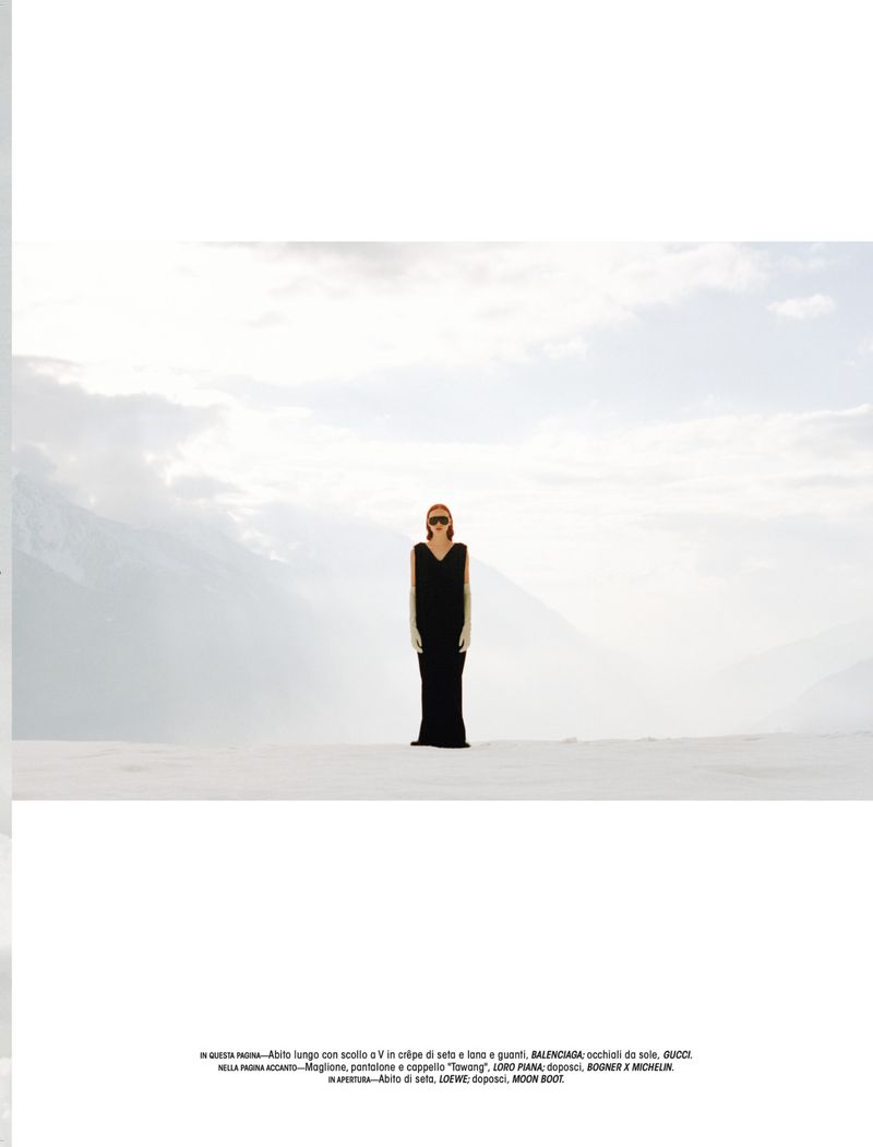 Model wearing a long black gown and sunglasses standing on a snowfield under an overcast sky for L'Officiel Italia.