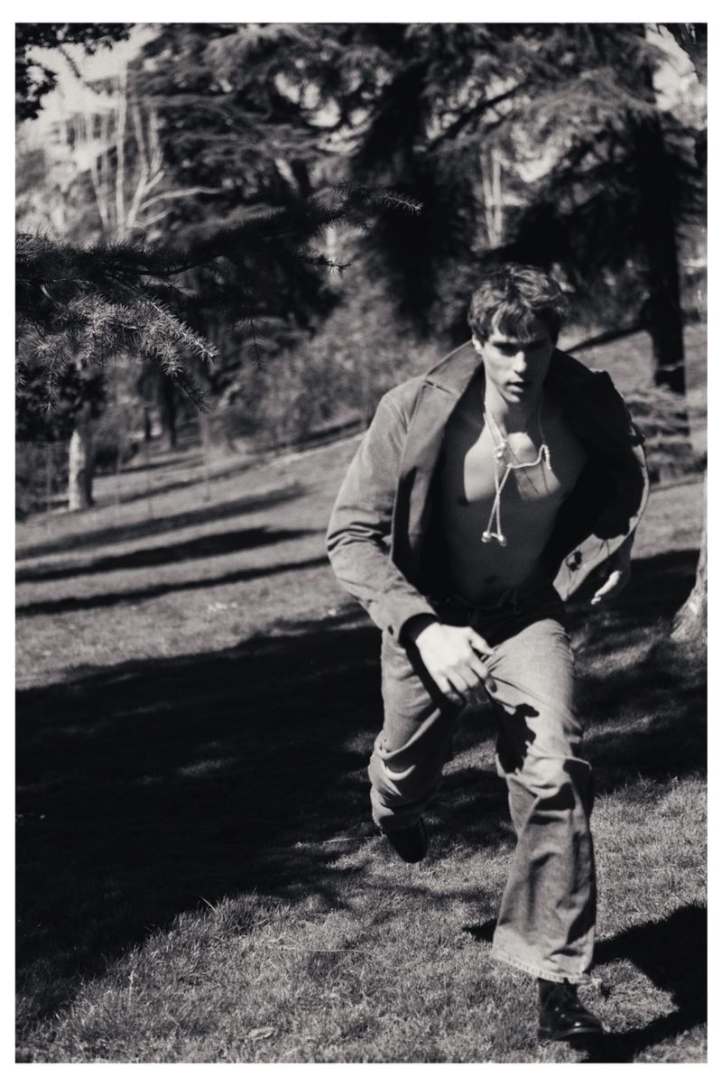Black and white portrait of a man running through a park in a jacket and jeans photographed by Tania Mendoza.