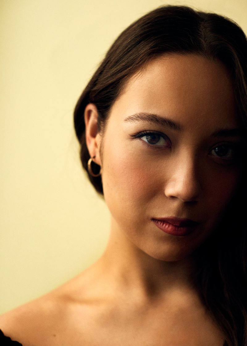Close-up portrait of singer Laufey against a pale yellow background for Billboard Magazine editorial.