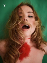 Portrait of Lexee Smith with blonde hair covering her mouth against a green background for Playboy, photographed by Morgan Maher.