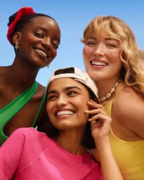 Three smiling women with diverse skin tones against a clear blue sky background for Sephora Australia.