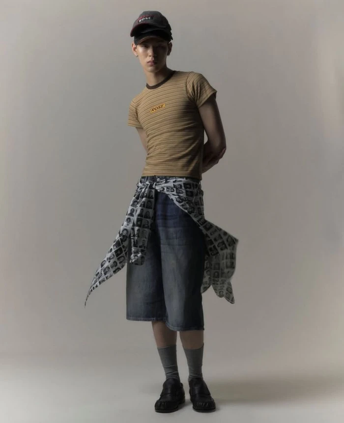 Model Jiho Kim wearing a striped t-shirt and denim shorts against a plain grey studio backdrop for LN-CC.