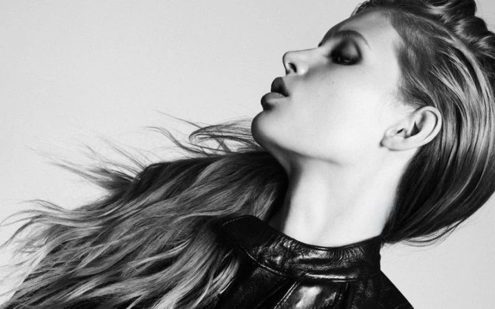 Profile portrait of model Ida Heiner with windswept hair wearing a dark leather jacket against a plain light background