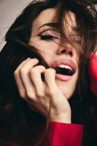 Close-up portrait of a woman with dark hair covering her face, wearing a red garment, captured by Rocio Ramos for Vanity Fair Espana.