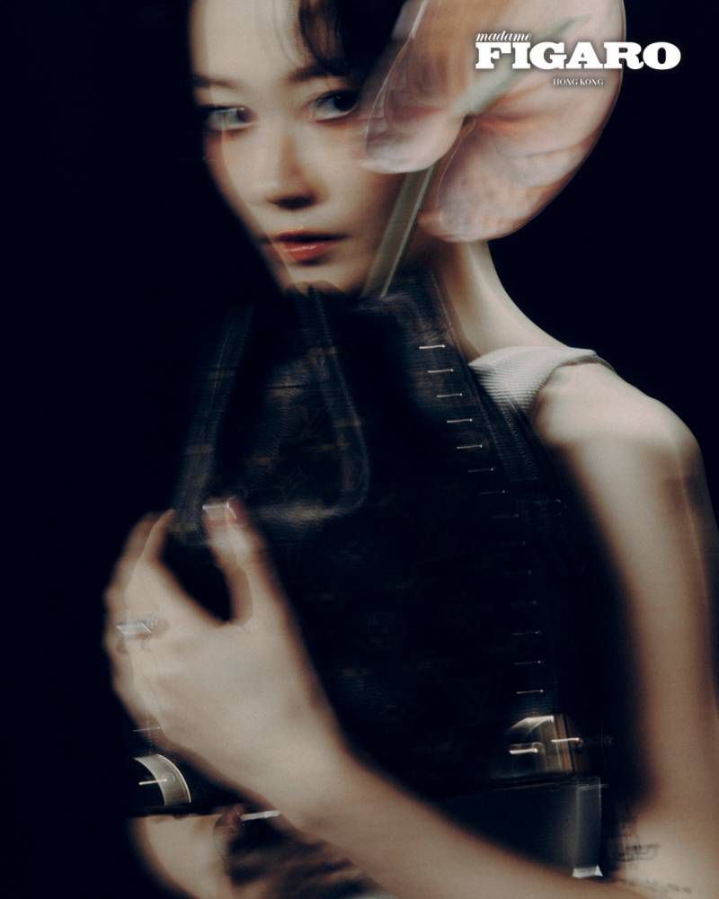 Portrait of a woman with dark hair holding a dark purse against a dark background, magazine cover featuring Madame Figaro text.