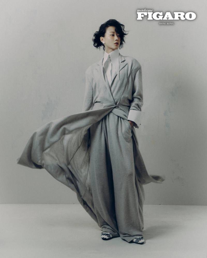 Woman in flowing grey suit and white shirt posing against a neutral grey studio background for Madame Figaro Hong Kong.