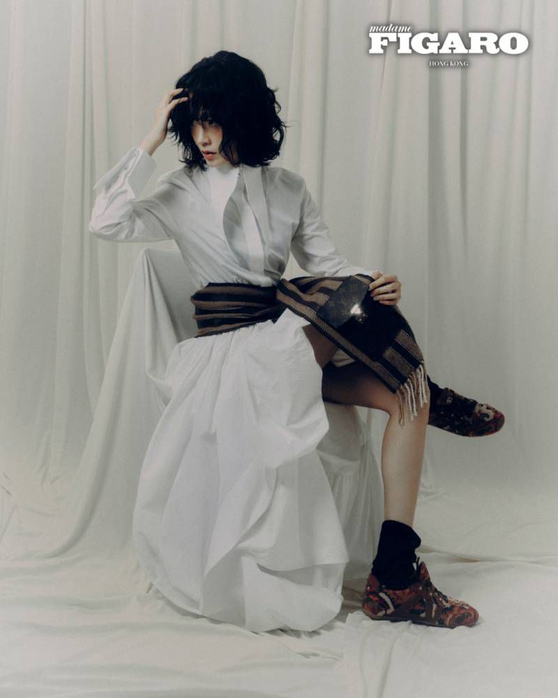 Woman in white dress and dark patterned scarf seated against draped white backdrop for Madame Figaro Hong Kong editorial