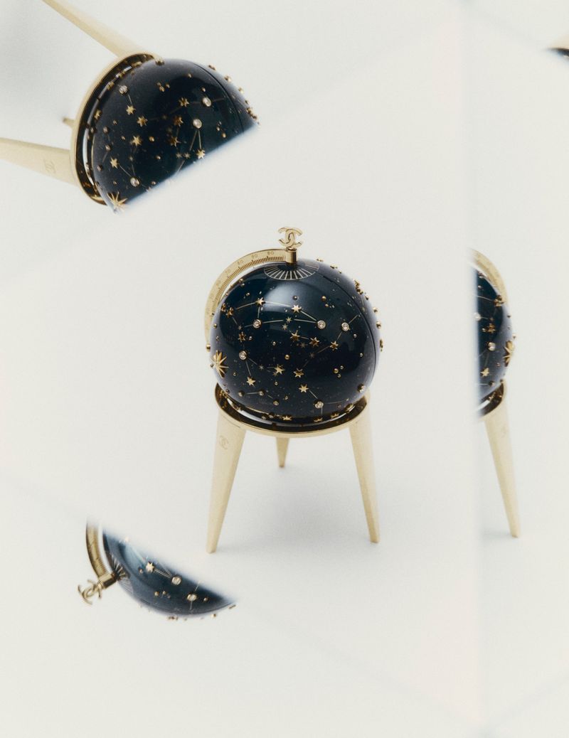 Close-up product shot of a dark blue celestial globe with gold star constellations on a white background
