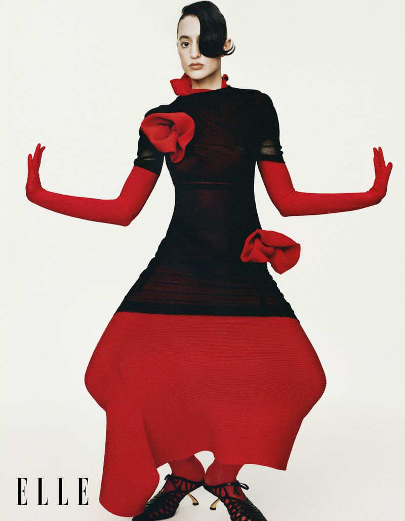 Model Aoife Lou in black dress with red gloves and skirt against white background for Elle China