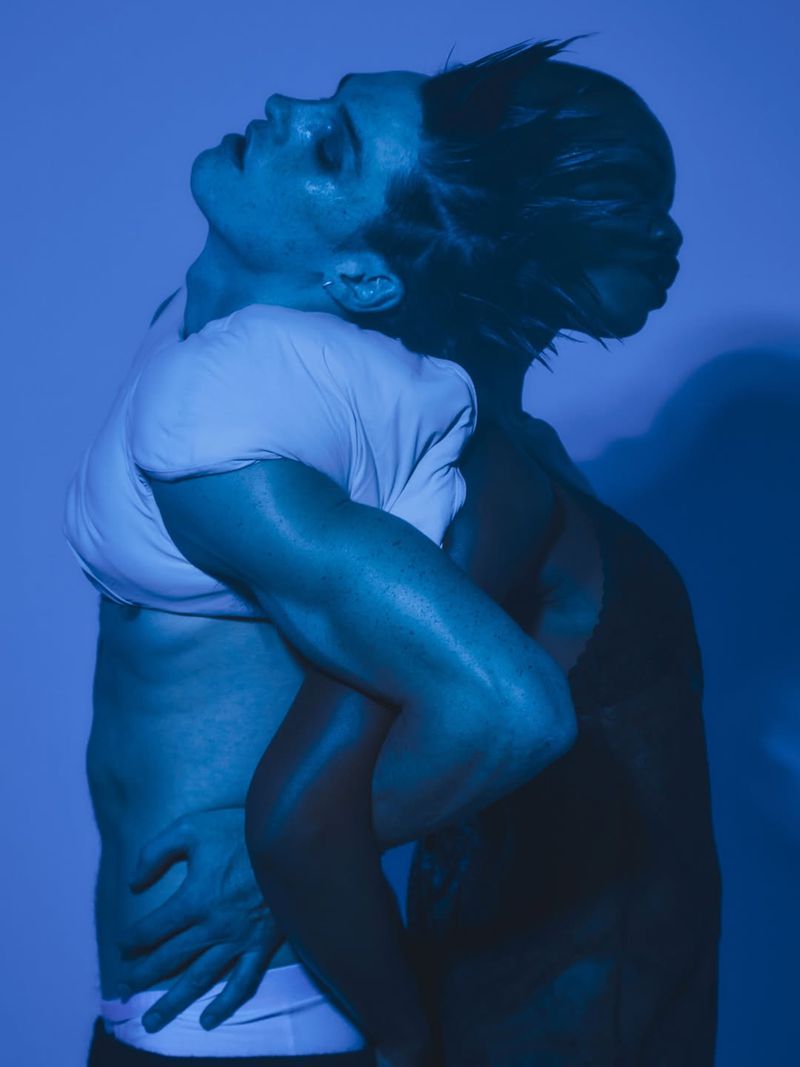 Two models embraced in profile under cool blue lighting for a Numero Netherlands fashion editorial.