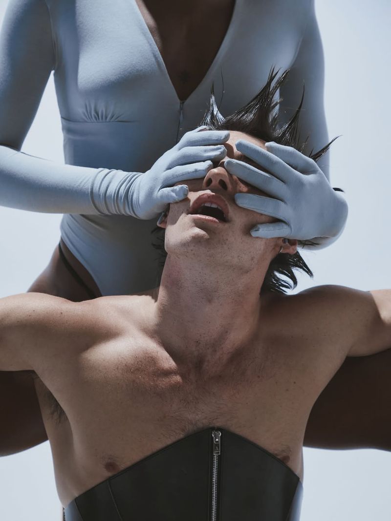 Model in blue gloves covering a man's eyes against a bright outdoor background for Numero Netherlands editorial.