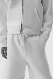 Close-up of a person wearing a white zip-up scuba hoodie and matching white shorts against a seamless white background.