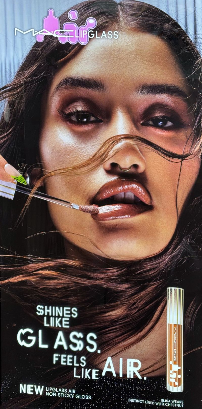 Close-up shot of a model with glossy lips, posing for a MAC lip gloss advertisement. The makeup artist applies lip gloss with wand.