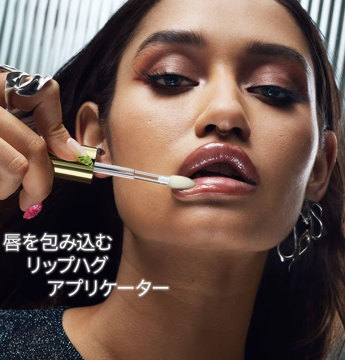 Close-up of a model applying glossy lip product with an applicator for MAC Cosmetics Lip Glass Air campaign