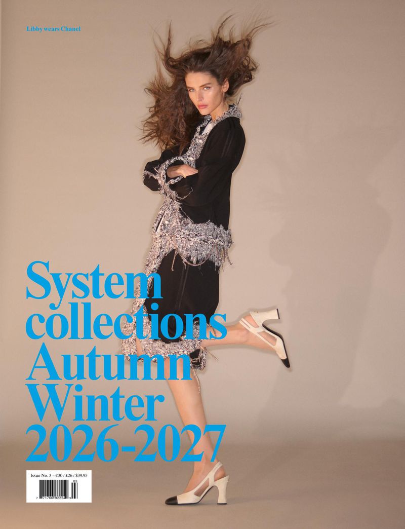 Model jumping in mid-air against a neutral studio backdrop, wearing a black and textured grey outfit with slingback heels.