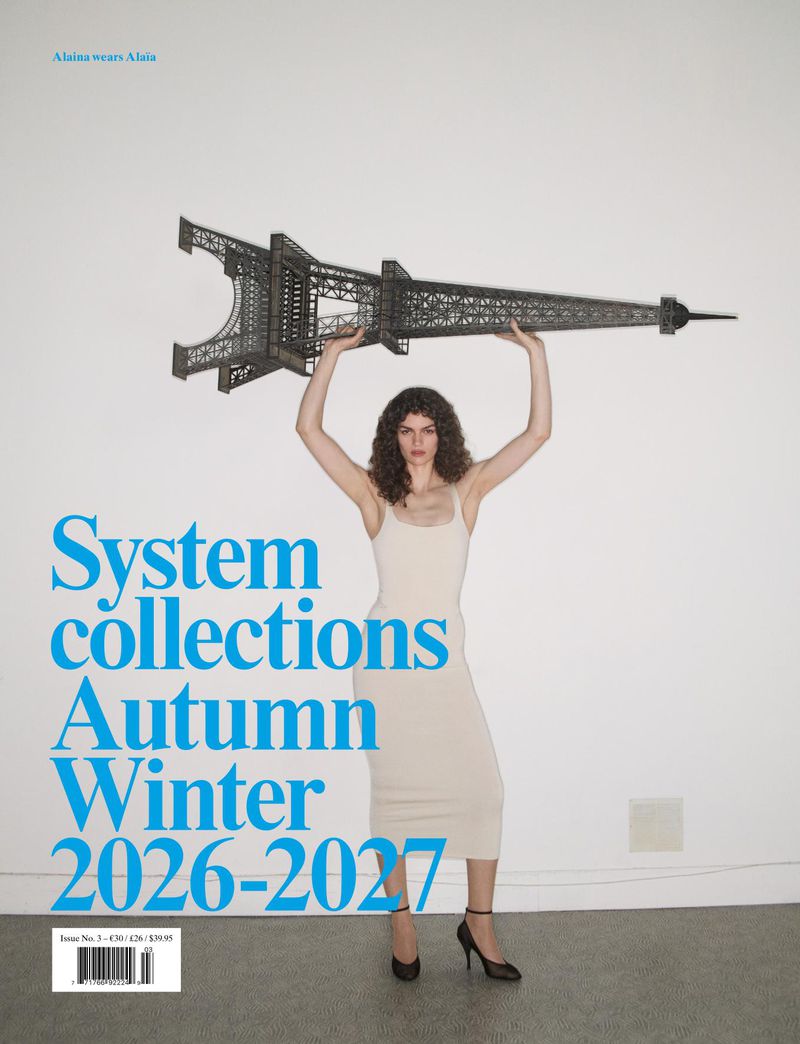 Model holding a miniature Eiffel Tower above her head against a plain white studio background for System Collections editorial.