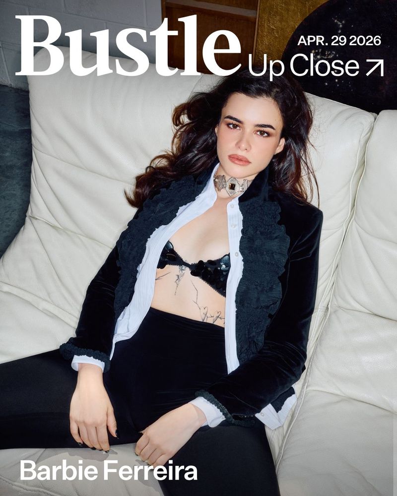 Barbie Ferreira on a white couch for Bustle Magazine cover, April 29 2026. She is wearing a black velvet jacket with a bra.