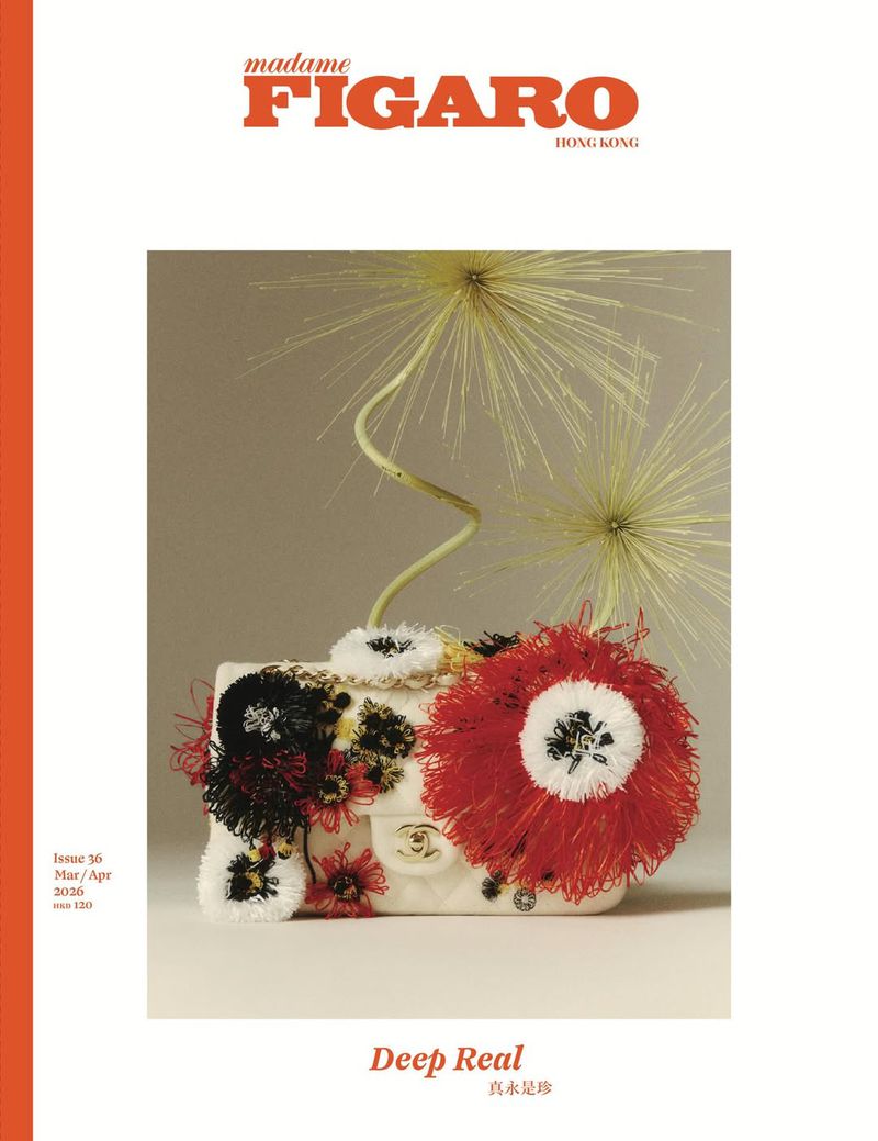 White quilted handbag decorated with red and black floral fringe, paired with organic seedpod stems in a studio setting.