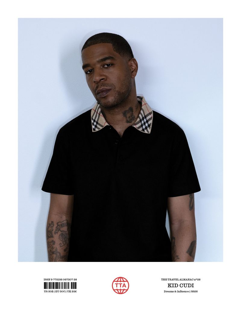 Portrait of Kid Cudi in a black polo shirt with patterned collar, posing against a neutral background in a studio environment.