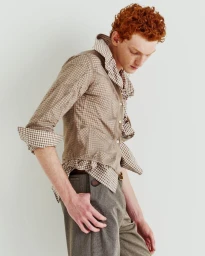 Red-haired male model wearing a checked shirt and grey trousers against a plain light background for Glass Man editorial.