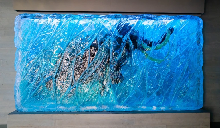 An illuminated blue faux ice sculpture of a woolly mammoth encased in a display frame for Colossal Biosciences Dallas HQ brand identity.