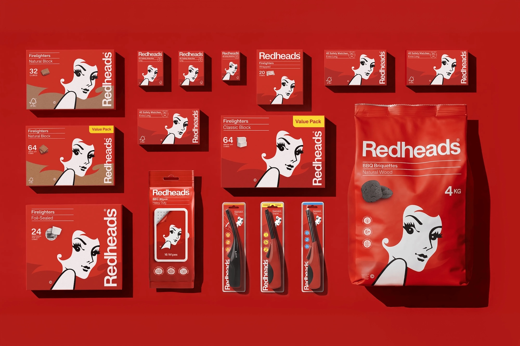Flat lay of Redheads brand packaging including matches boxes, firelighter blocks, and a large charcoal bag on a red background.