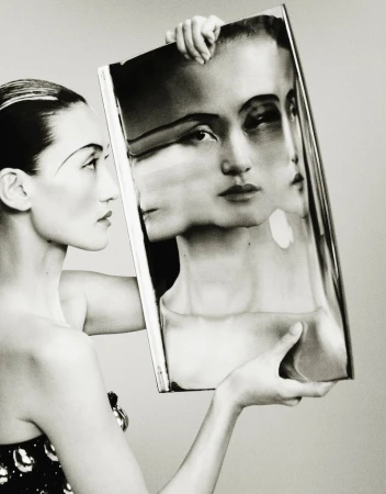 Monochrome fashion shot of an Asian woman in elegant dress holding a framed picture of her face, creating a multi-face portrait.