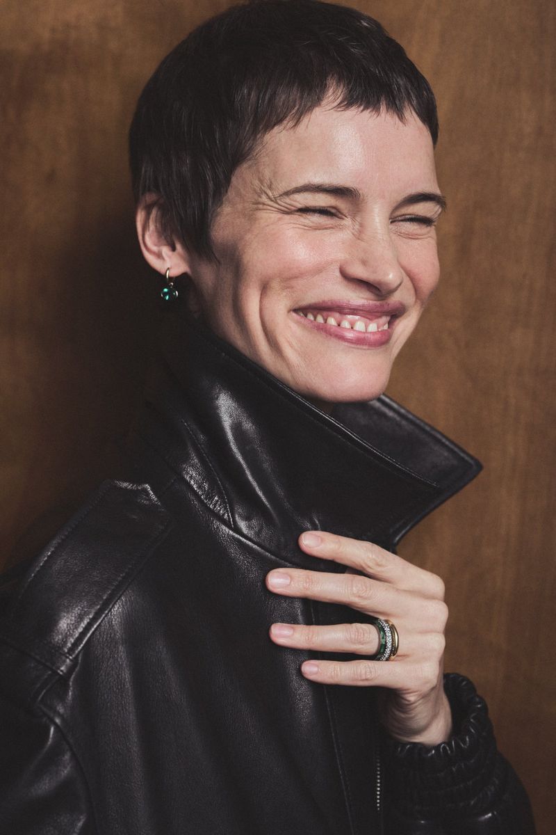 Close-up portrait of a smiling short-haired woman wearing a black leather jacket and delicate rings by Jem Mitchell for By Pariah.