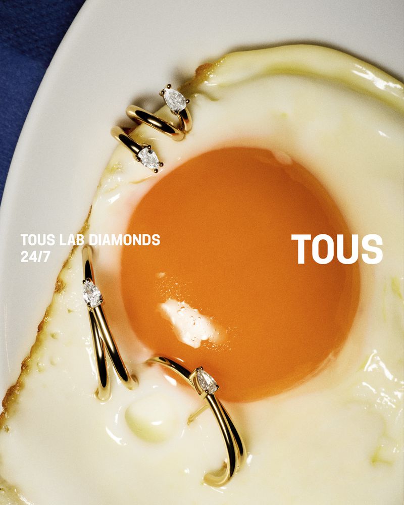 Close-up of gold diamond rings arranged around the vibrant orange yolk of a fried egg on a white plate with text overlays.