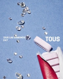 Scattered loose lab-grown diamonds next to a partially unwrapped pack of pink chewing gum on a textured blue surface.