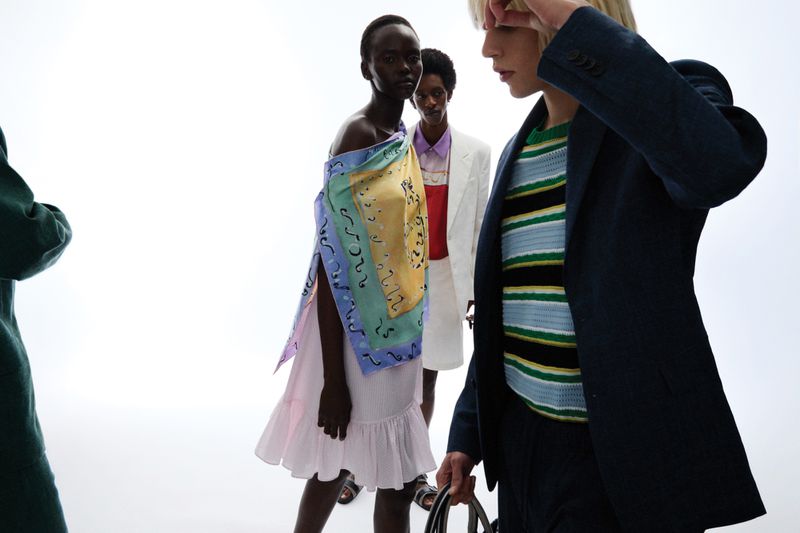 Group of four models in colorful designer clothing posing against a bright white background for Schön Magazine.