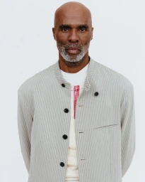 Portrait of a mature Black man wearing a striped jacket against a plain white background