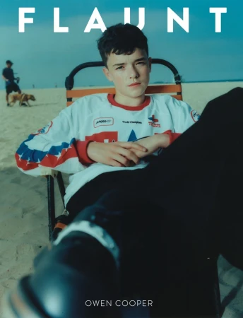 Portrait of a young adult male in a vintage hockey jersey, sitting on a beach chair near the ocean, with text overlay: FLAUNT and OWEN COOPER.