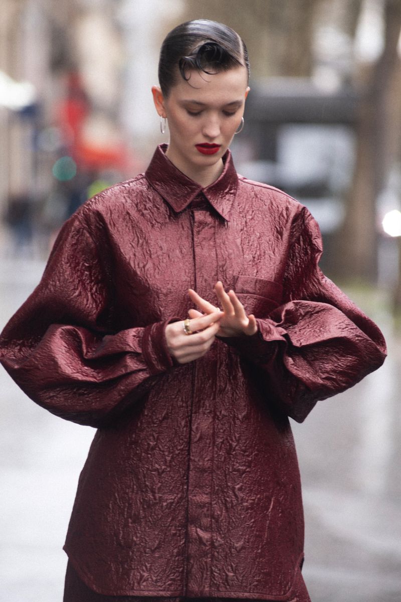 Model in a textured burgundy shirt standing on a city street for an editorial shoot by Elle Hungary