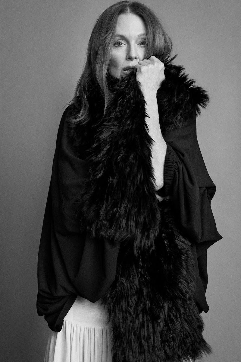 Julianne Moore wearing a black fur stole and dark dress against a plain grey studio backdrop in a portrait by Paul Wetherell.
