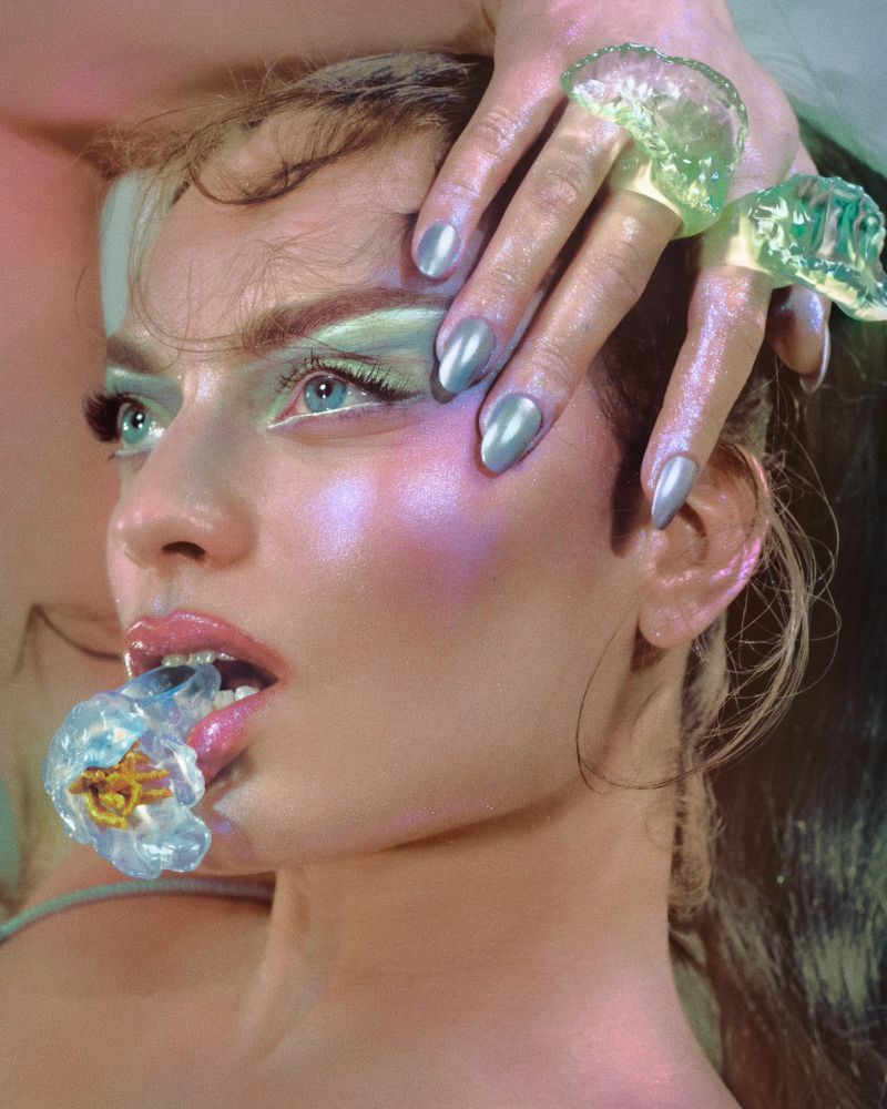 Close-up portrait of a woman wearing resin rings and holding one in her mouth, photographed by Elizaveta Porodina.