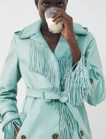 Model Aluel Keror wearing a mint green fringed leather coat drinking from a glass for Exit Magazine by photographer Maona Micoud