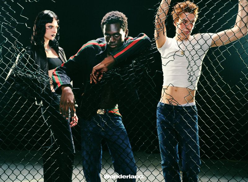 Three models posing behind a chain-link fence for a Wonderland China fashion editorial project.