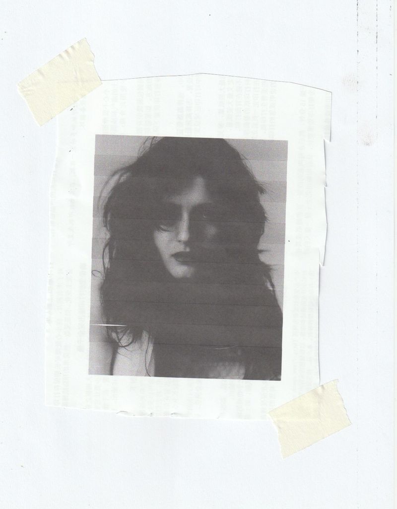 Monochrome portrait of a woman with dark wavy hair taped to a paper background with adhesive tape