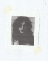 Monochrome portrait of a woman with dark wavy hair taped to a paper background with adhesive tape