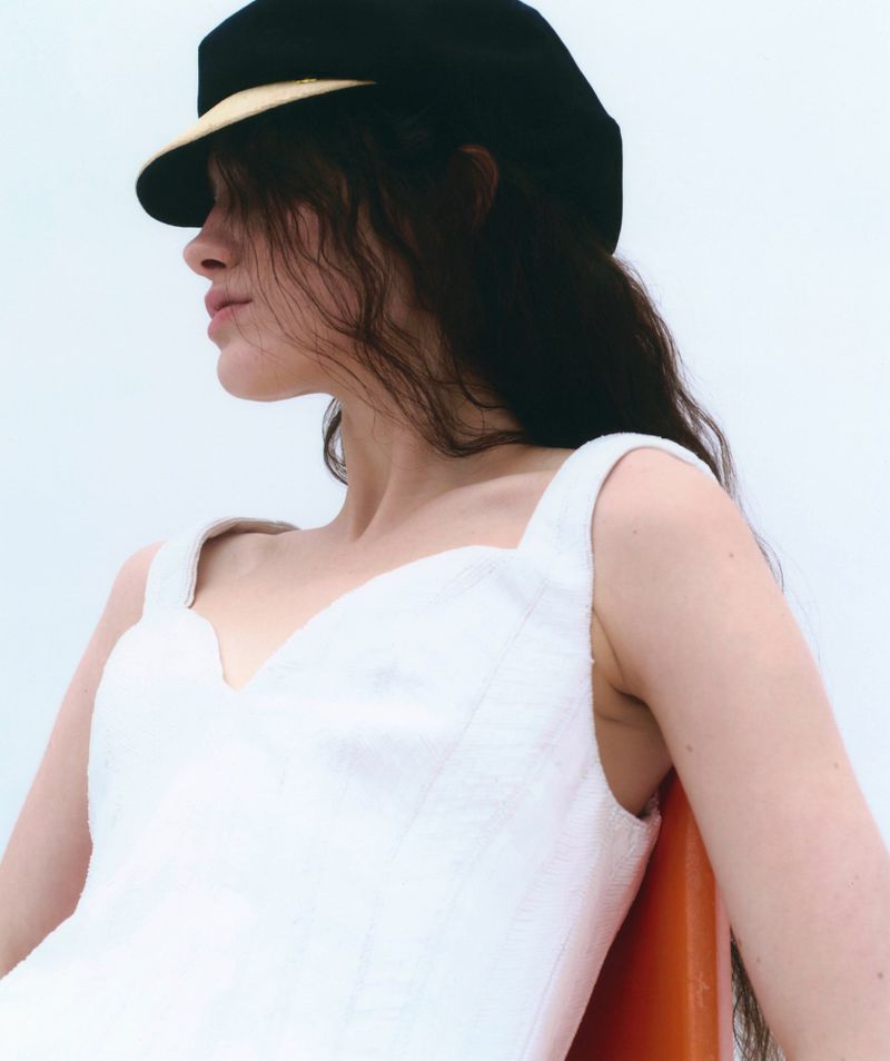 Model wearing a white dress and black cap against a neutral background for Silhouette Magazine