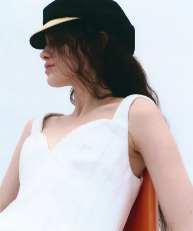 Model wearing a white dress and black cap against a neutral background for Silhouette Magazine