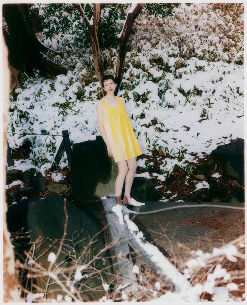 Model in a yellow dress standing outdoors in a snow-covered park for Grazia Malaysia Tokyo Park project