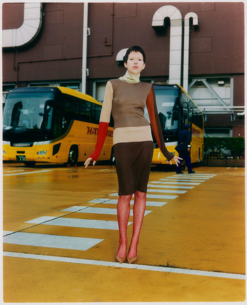 Model wearing colour-blocked dress standing on yellow asphalt between two buses for Grazia Malaysia Tokyo Park editorial