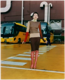 Model wearing colour-blocked dress standing on yellow asphalt between two buses for Grazia Malaysia Tokyo Park editorial