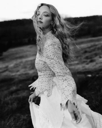 Black and white portrait of Amanda Seyfried wearing a patterned lace top outdoors in a field