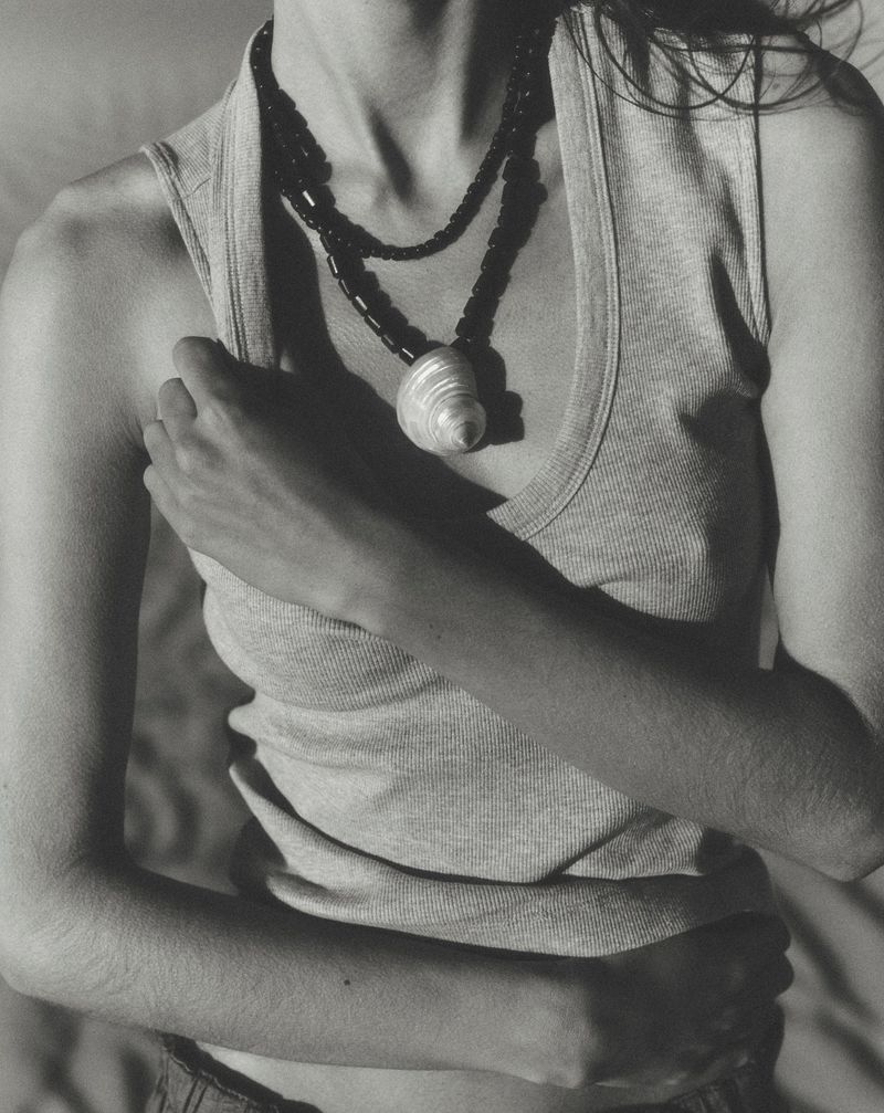Close-up of a model wearing a ribbed tank top and a statement shell necklace for Anthropologie.