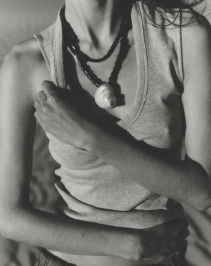 Close-up of a model wearing a ribbed tank top and a statement shell necklace for Anthropologie.
